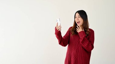 Akıllı telefon ekranına bakan genç Asyalı kadın şaşırdı ve şaşırdı. Alışveriş başvurusunda ateşli bir online satış promosyonuyla şaşırdı. beyaz arkaplanda izole