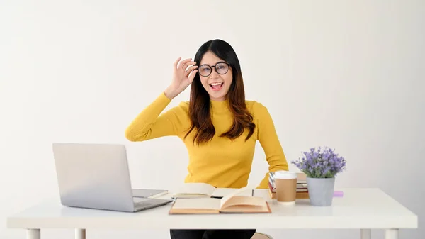 stock image A smart and happy young Asian female college student is touching her glasses while studying online at her house. isolated on white background