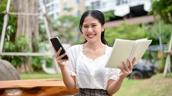 Una Hermosa Feliz Joven Asiática Sostiene Libro Teléfono Inteligente Mientras — Foto de Stock