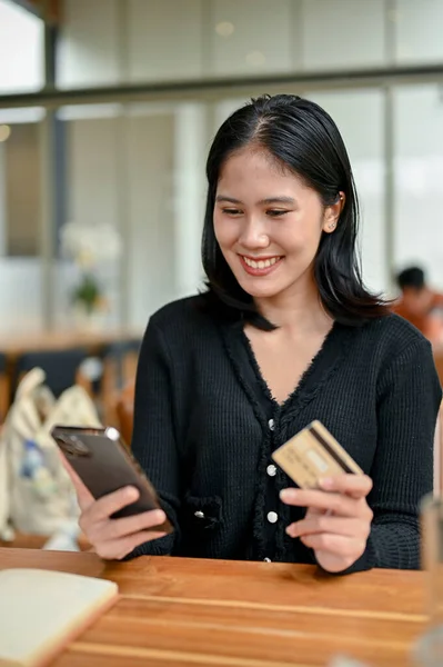 一张漂亮的亚洲女人的肖像 她在咖啡店休息的时候 用她的手机银行申请来支付她的网上购物费用 — 图库照片