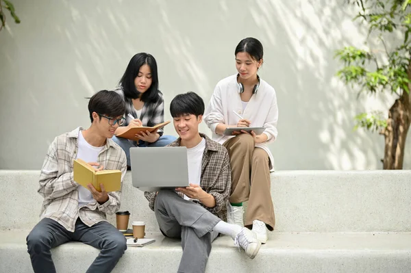 一群年轻的亚洲大学生坐在校园休闲区的长椅上 一起做作业或辅导 准备考试 教育概念 — 图库照片