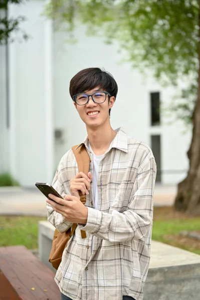 Розумний Студент Азіатського Коледжу Окулярах Рюкзаком Смартфоном Руці Стоїть Кампусі — стокове фото