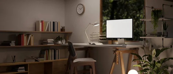 窓に対するテーブル 壁に対する本棚 および装飾にコンピュータの白いスクリーンモックアップと夜のミニマリストで快適なホームオフィスのインテリアデザイン 3Dレンダリング 3Dイラスト — ストック写真