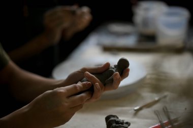 Yakından bakınca, kil heykel atölyesindeki bir adamın, stüdyodaki bir masada süs yapmak için işlenmemiş kil kalıbı çıkardığı görülüyor. El işi, heykeltraş, zanaatkar