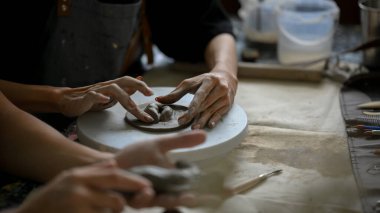 Küçük bir çömlek çarkına işlenmemiş kil şekillendiren ya da şekillendiren bir erkeğin yakın plan resmi, atölyede el yapımı kil süsü yapıyor. Sanat atölyesi, eğlence, yaşam tarzı