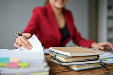 Modern ofisindeki masasında iş raporları üzerinde çalışan Asyalı profesyonel bir iş kadınının yakın plan resmi..