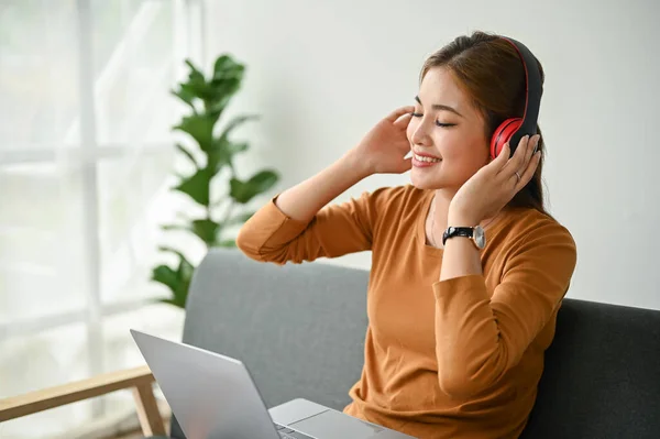 아름다운 아시아의한 여성은 거실에 소파에서 헤드폰으로 음악을 듣기를 즐긴다 — 스톡 사진