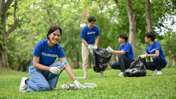 美しい笑顔の若いアジアの女性ボランティアは 彼女のチームが公園内のエリアをきれいにするのを助けています チャリティーイベントボランティア活動Csrプロジェクト — ストック写真
