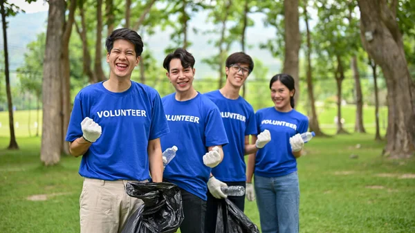 一群拿着垃圾袋的年轻的亚洲志愿者站在公园里 展示他们的拳头 志愿工作 支助社区 回收利用 — 图库照片