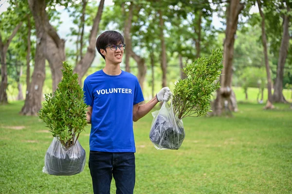 一位快乐的年轻亚洲男性志愿者手拿着植物散步 为他们的社区公园种花 志愿工作 生态和社区可持续性概念 — 图库照片