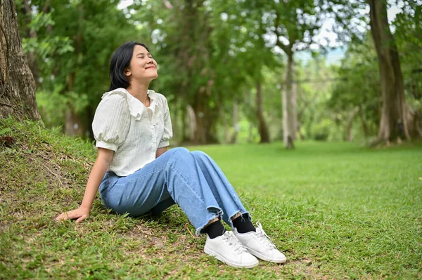 Vacker Asiatisk Kvinna Avslappnade Kläder Sitter Gräset Ett Träd Park — Stockfoto