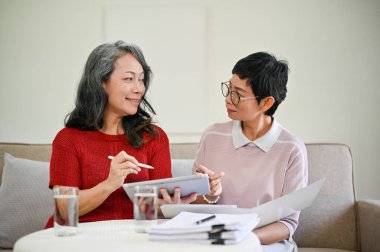 Orta yaşlı, güzel bir Asyalı kadın sağlık sigortacısı iş yapmak ve yeni bir sigorta sözleşmesi yapmak için emekli bir kadını ziyaret etti..