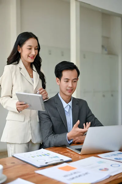 A beautiful and successful millennial Asian businesswoman or female boss is briefing work and co-working with a smart male financial analyst in the office.