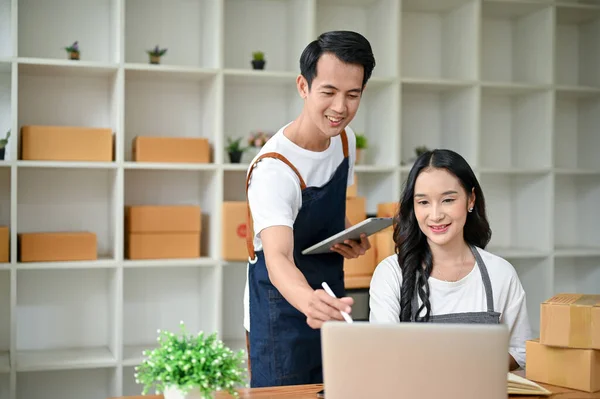 A successful Asian online seller couple is checking online orders, updating new products on the website, and working in their home office together. online shopping, SME business