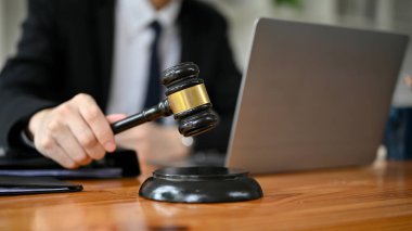 Profesyonel bir erkek avukatın mahkeme salonundaki masasında yargıç tokmağı tutarken yakın plan görüntüsü. Avukat, avukat, noter, avukat.