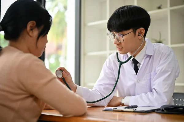 一位专注而专业的千年亚洲男医生在医院用听诊器检查女病人的心跳 体格检查 医疗概念 — 图库照片