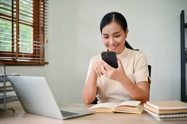 Fiatal Bájos Ázsiai Használja Okostelefonját Miközben Otthon Asztalánál — Stock Fotó