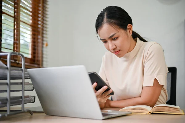 stock image Young stressful woman working from home with smartphone and laptop computer.