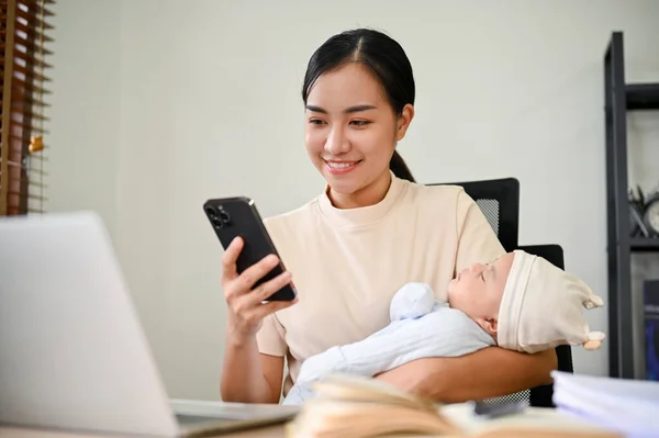 집에서 일하고 전화로 이야기하고 아기를 아시아의 아름다운 어머니 — 스톡 사진