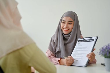 Genç Müslüman emlakçı müvekkiline irtibat anlaşmasını açıklıyor. İş insanları kavramı