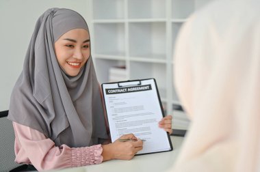 Genç Müslüman emlakçı müvekkiline irtibat anlaşmasını açıklıyor. İş insanları kavramı