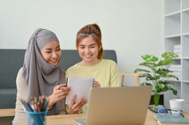 Bir grup genç öğrenci zamanlarında birlikte okuyorlar. Müslüman bir kadın arkadaşıyla kitap okuyor.. 