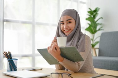 Genç ve güzel iş kadını boş zamanlarında kitap okuyor ve bir fincan kahve içiyor.. 