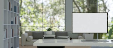 Masaüstü bilgisayarı gibi arka plan olarak kitap rafı olan minimal modern çalışma odası. 