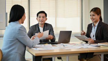 Profesyonel bir Asyalı erkek patron toplantıda pazarlama ekibiyle yeni bir projeyi tartışıyor..