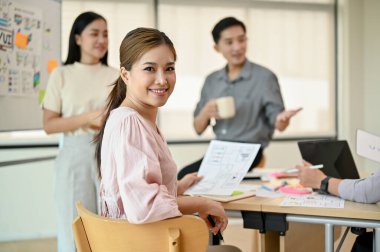 Çekici bir Asyalı kadın müteahhit, yeni mobil uygulama projesi için iş arkadaşlarıyla toplantıda..