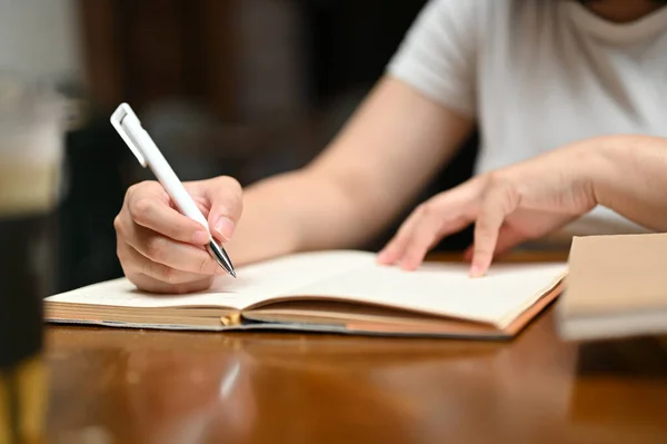 カフェのテーブルで本に何かを書いている女性のクローズアップイメージ 日記を書いてメモをとってリストを作る — ストック写真