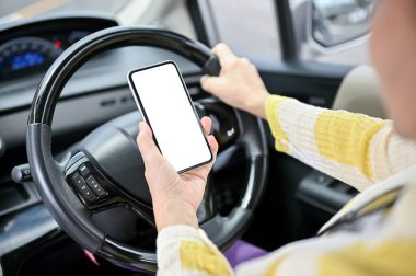 Araba kullanırken akıllı telefonunu kullanan Asyalı bir kadının yakın plan görüntüsü. akıllı telefon beyaz ekran modeli