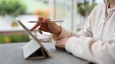 Hafta sonu bir kafede otururken dijital tabletini kullanan Asyalı bir kadın serbest çalışanın yakın plan görüntüsü. dijital göçebe, uzak çalışma