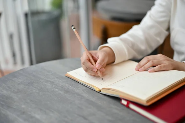 喫茶店のテーブルに座りながらノートに何かを書いている女性のクローズアップイメージ 宿題日記メモをとって — ストック写真