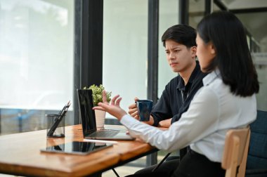 İki ciddi ve profesyonel Asyalı ofis çalışanı birlikte bir kahve dükkanında çalışıyorlar, iş tartışıyorlar ve ortak projelerine odaklanıyorlar..