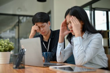 İki ciddi ve stresli Asyalı ofis çalışanı proje sorunlarına çözüm bulmak ve planlamak için birlikte projelerine odaklanıyorlar..