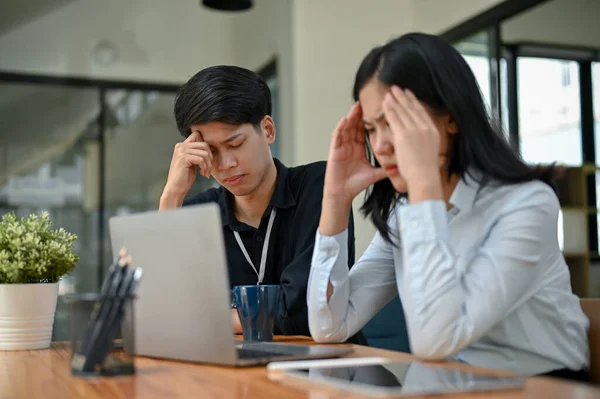 stock image Two serious and stressed Asian office workers are focusing on their co-project together, planning and finding solutions to their project problems.