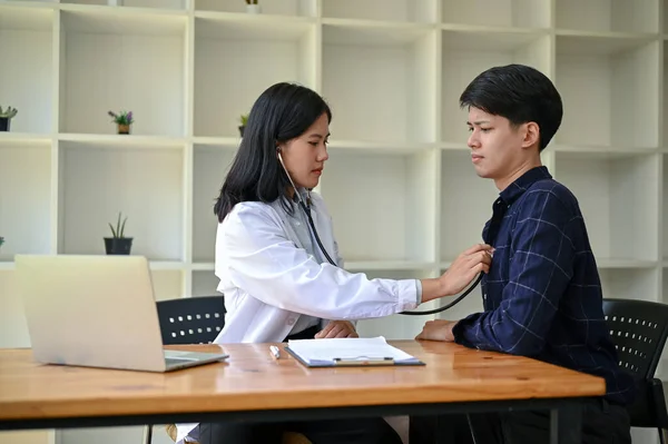 一名专业的亚洲女医生在医院进行体格检查时 用听诊器检查和听病人的心跳 — 图库照片