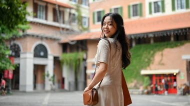An attractive young Asian woman in casual clothes enjoys strolling in the city alone on her weekend. lifestyle concept