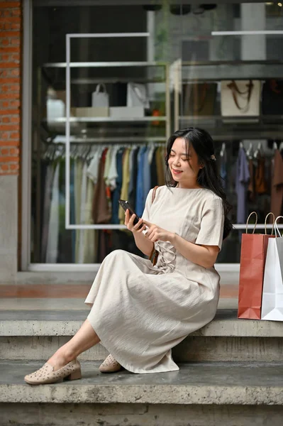 Charming Young Asian Woman Texting Her Friends Her Smartphone While — Stockfoto