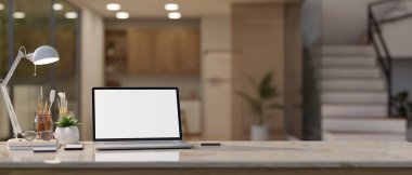 Laptop beyaz ekran modeli, masa lambası, aksesuarlar ve arka plan olarak bulanık oturma odası olan bir masa üstü fotokopi alanı. 3d görüntüleme, 3d illüstrasyon