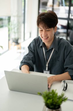 Zeki ve yakışıklı Asyalı genç bir iş adamının portresi. Ya da modern bir ofiste bilgisayarında çalışan erkek bir mühendisin..