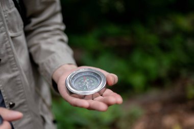 Ormanda tek başına yürürken pusula tutan bir erkek yürüyüşçünün yakın plan görüntüsü. yön, rehberlik, navigasyon, ekipman