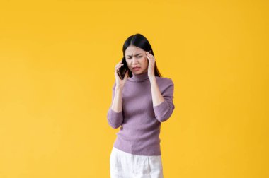 Stresli ve tatminsiz bir Asyalı kadın telefonda birisiyle konuşuyor, kafası karışık ve bir şeyden emin değil. izole edilmiş sarı arkaplan.