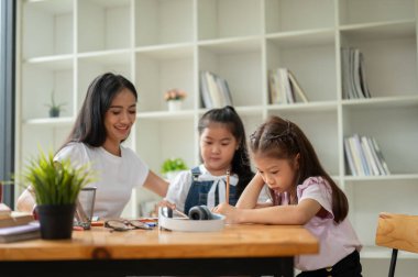 Odaklanmış Asyalı genç bir ilkokul öğrencisi, evde arkadaşıyla birlikte özel bir öğretmenle ders çalışıyor. Ekstra öğretim sınıfı konsepti