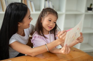 Nazik ve güzel bir Asyalı anne genç kızıyla evde resim çizmekten hoşlanır. Mutlu aile kavramı