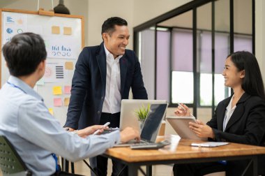 Neşeli bir Asyalı işadamı, toplantı odasında ekibiyle fikir paylaşımı ve beyin fırtınası yapmaktan zevk alır..