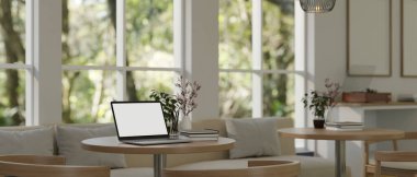 Samimi, minimalist bir kahve dükkanında çalışma alanındaki bir masada dizüstü bilgisayarın beyaz ekran modeli. 3d görüntüleme, 3d illüstrasyon