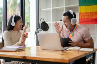 Çekici ve neşeli bir Asyalı gay podcaster ya da radyo sunucusu gülüyor, komik hikayeler anlatıyor ve stüdyodaki ses kaydı sırasında konuğuyla röportaj yapmaktan zevk alıyor..