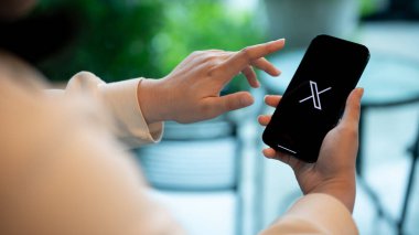 Chiang Mai, Tayland - 14 Ağustos 2023: Bir kafede otururken X yeni twitter uygulaması kullanan bir kadın. Görüntüyü yaklaştır. İnsanlar ve yaşam tarzı kavramı